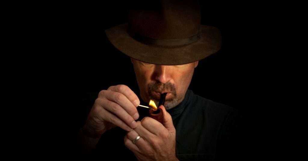 man lighting a tobacco pipe