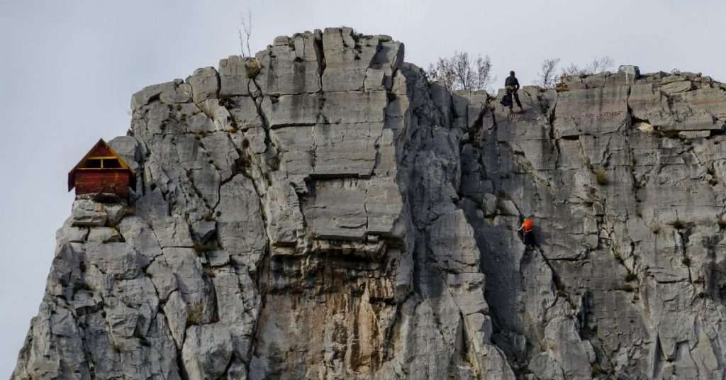 men in middle of rock face
